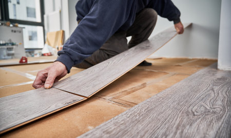 Close up of man hands laying laminate wooden planks on the floor in apartment under renovation. Male construction worker installing timber laminate flooring at home. Hardwood floor renovation concept.の写真素材