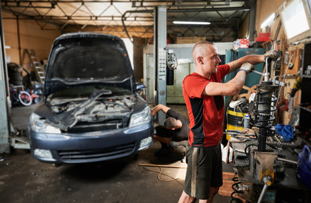 Professional mechanic, repairman, worker holding screwdriver, fixing car. Hardworking man standing in workshop, garage, working with equipment. Concept of manual work.の写真素材