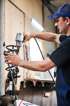 Professional worker, repairman, mechanic working in garage, workshop. Man wearing cap and uniform, holding, using equipment, instrument. Concept of manual labor.の写真素材