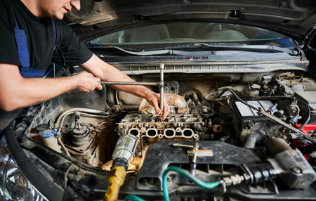 Worker, repairman fixing car engine, opening hood of car, repairing, fixing problem. Close up mechanic working in auto servicing center.の写真素材
