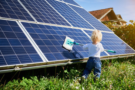 Small boy learning how to care about solar panels. Young kid cleaning new solar battery at warm day. Concept of young generation and alternative energy.の写真素材