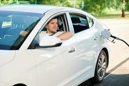 Man waiting for his car will be refueled. Confident man looking through window of auto if tank is filled.の写真素材