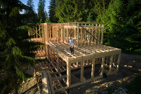 Investor is funding the construction of wooden frame house near the forest. The concept behind it is modern and environmentally friendly construction.の写真素材