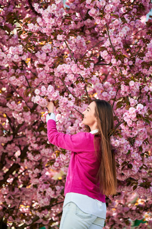 Woman allergic enjoying after treatment from seasonal allergy at spring. Portrait of happy beautiful woman smiling in front of blooming sakura tree at springtime. Spring allergy concept.の写真素材