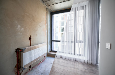 Comparison of apartment flat before and after restoration or refurbishment. Photo collage of old room with large windows and new renovated room with heating radiator, parquet floor and white walls.の写真素材