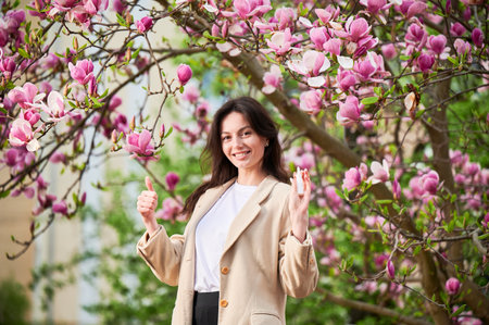 Woman allergic using medical nasal drops, suffering from seasonal allergy at spring in blossoming...