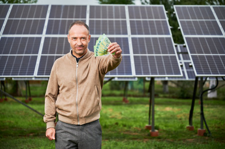 Knowledgeable man showing money he earning by investing in green energy. Promising industry of alternative energy sources. Male glad of his decision to invest in modern resources.の写真素材