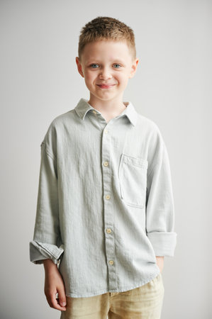 Portrait of happy boy in casual clothes keeping hand in pocket. Adorable boy smiling to camera. Stylish kid posing on white background.の写真素材