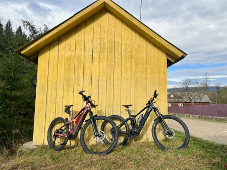 Two modern electric mountain bikes leaning to small wooden house (no people).の写真素材