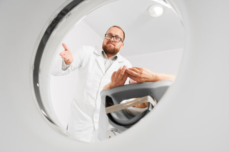 Medical computed tomography or MRI scanner. Male radiologist examine female patient, looking to the camera. Concept of modern diagnostics.の写真素材