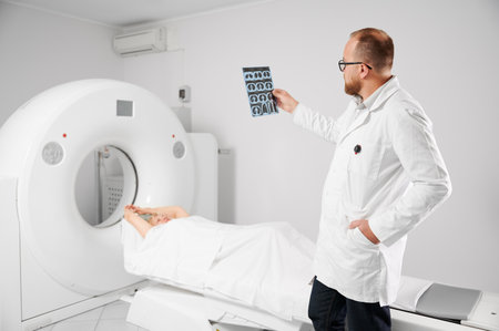 Medical computed tomography or MRI scanner. Doctor holding and examining results of MRI. Woman patient lying on couchette. Concept of medicine, healthcare and modern diagnostics.の写真素材