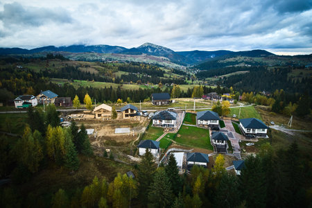 Aerial view of holiday cottages in mountains. Rest houses with photovoltaic solar panel system on roof in coniferous forest. Relaxing far from big city.の写真素材