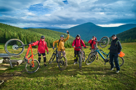 Group of cyclists men riding electric bikes outdoors. Portrait of happy tourists resting on the top of hill, enjoying beautiful mountain landscape. Concept of sport, active leisure and nature.の写真素材