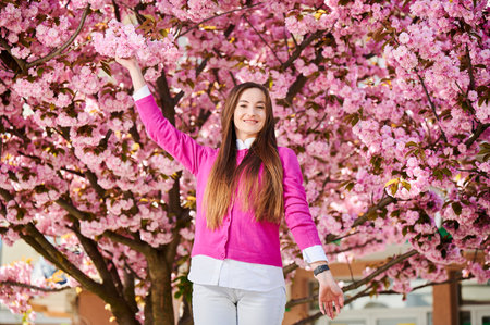 Woman allergic enjoying after treatment from seasonal allergy at spring. Portrait of happy beautiful woman smiling in front of blooming sakura tree at springtime. Spring allergy concept.の写真素材