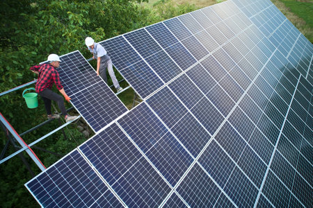 Aerial view of men technicians installing photovoltaic solar panels to high steel platform. Concept of alternative energy.の写真素材