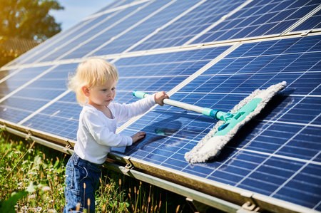 Little kid learning how to clean solar panel. Young boy learning how to care about solar station. Concept of young generation and green energetic.の写真素材