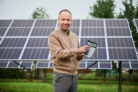 Happy man showing his future profit from investing in solar panels. Knowledgeable man glad about his investment in green energy.の写真素材