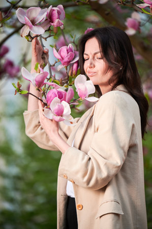 Woman allergic suffering from seasonal allergy at spring, posing in blossoming garden at springtime. Portrait of young woman sneezing among blooming trees. Spring allergy conceptの写真素材