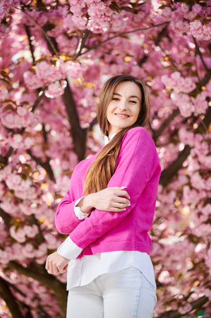 Woman allergic enjoying after treatment from seasonal allergy at spring. Portrait of happy beautiful woman smiling in front of blooming sakura tree at springtime. Spring allergy concept.の写真素材