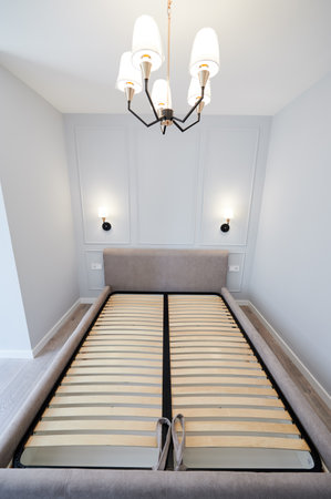 Bedroom with large bed, white walls and lamps in apartment after renovation. Interior of modern apartment with elegant minimalist design and comfortable sofa bed.の写真素材