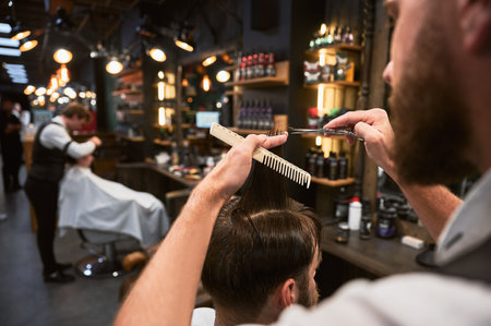 Close-up photo of barber cutting wet hair. Professional hairdresser making fresh hairstyle. Back view of man getting new haircut.の写真素材