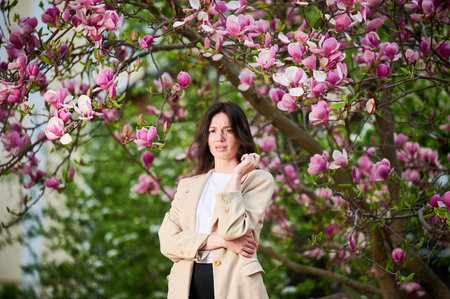 Woman allergic suffering from seasonal allergy at spring in blossoming garden at springtime. Young woman sneezing, having runny nose in front of blooming tree. Spring allergy conceptの写真素材