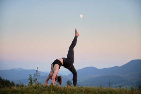 Woman practicing yoga outdoors in the mountains in a serene, natural setting. Female performing yoga...