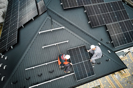 Installers building photovoltaic solar module station on roof of house. Men electricians in helmets installing solar panel system outdoors. Concept of alternative and renewable energy. Aerial view.の写真素材