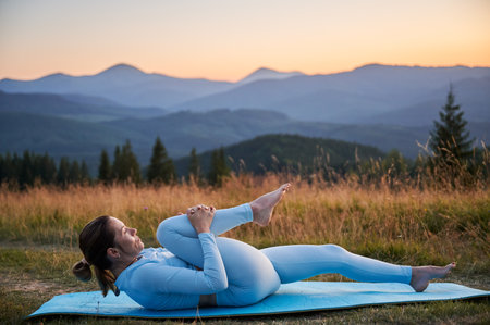 Woman practicing yoga outdoors in the mountains in a serene, natural setting. Female performing yoga...
