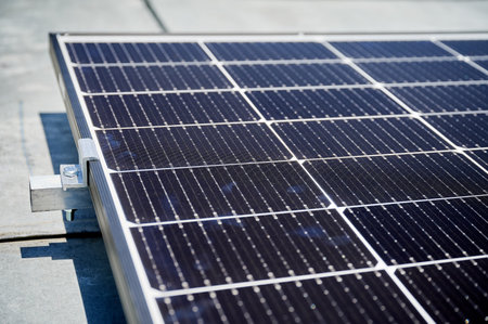 Close up of solar panel, securely fastened with robust mounting clamp to supporting structure. Critical components such as bolts and clamps provide stability and durability to solar installation.の写真素材