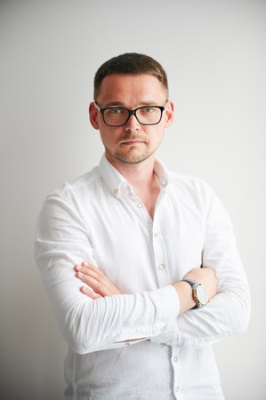 Portrait of man with serious, confident expression on his face. Handsome young male in casual clothes keeping arms crossed while standing on white background.の写真素材