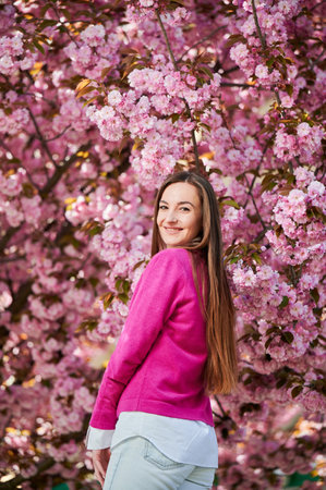 Woman allergic enjoying after treatment from seasonal allergy at spring. Portrait of happy beautiful woman smiling in front of blooming sakura tree at springtime. Spring allergy concept.の写真素材