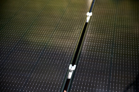 Close up of mounting hardware on solar panel, focusing on the details of the securing mechanism. Bolt and mounting structure against the blurred lines of photovoltaic cells stretching into background.の写真素材