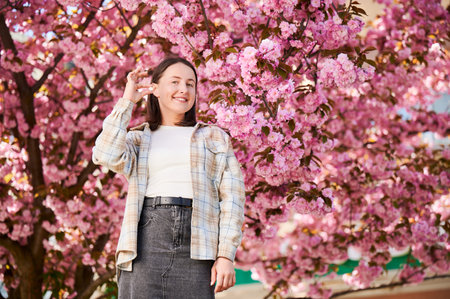 Woman allergic suffering from seasonal allergy at spring. Young happy woman showing allergy pill, posing in blossoming garden at springtime. Antihistamine medication conceptの写真素材