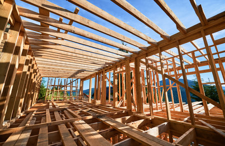 Residential wooden frame building in progress near a forest. Start of new construction of comfortable house. The idea of modern ecological building techniques and contemporary architecture.の写真素材
