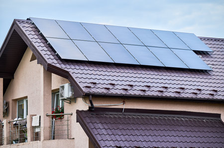 House with solar panels on rooftop for generating electricity through photovoltaic effect. Home with...