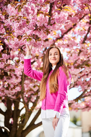Woman allergic enjoying after treatment from seasonal allergy at spring. Portrait of happy beautiful woman smiling in front of blooming sakura tree at springtime. Spring allergy concept.の写真素材