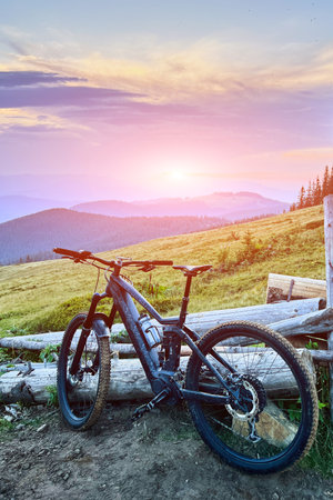 Black electric mountain bike on the dirt trail in the mountains at sunset (no people).の写真素材