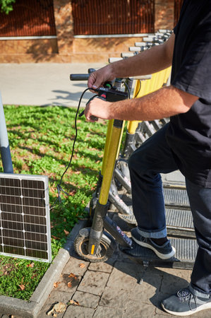 Man connects solar panel to electric scooter for charge, highlighting practical application of...