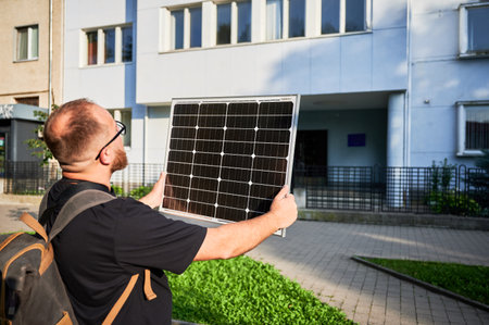 Man holding photovoltaic solar panel in front of historical building. Concept of integration of sustainable renewable energy sources into architecture.の写真素材
