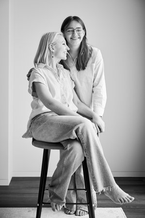 Cute family moment of mom and daughter hugging. Portrait of teenage girl showing her love to mother. Two female in casual clothes smiling and hugging at home. Black and white image.の写真素材
