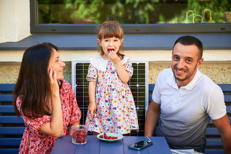 Happy family spending time together at sunny day. Little girl smiling to her parents. Young couple...