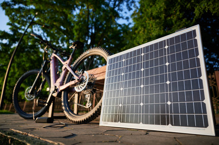Pink electric mountain bike parked beside wooden bench, connected to solar panel for charging. On...