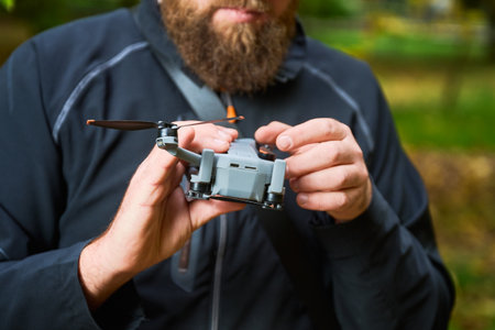 A person carefully inspects a small drone in a lush forest setting, blending technology with the...