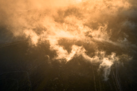 Stunning aerial view of mountain landscape at sunrise, with suns golden rays piercing through mist...