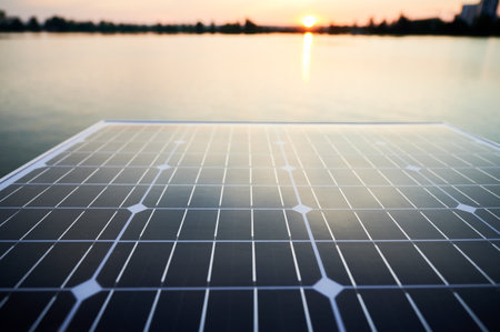 Solar panel with sun setting over calm lake in background. Peaceful ambiance of renewable energy technology in harmony with nature, highlighting sustainability and innovation.の写真素材