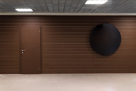 Brown wall with door and blank round place for a text in business center. Airportの写真素材