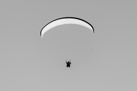 Paragliding in mountains in spring time. Blank space for a text. Black and white picture. Men in the center. Georgia, Gudauri.の写真素材