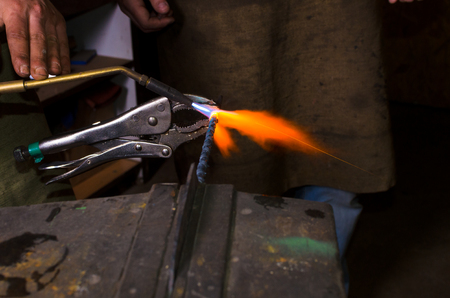 Heating metall by gas burner in forge workspaceの写真素材