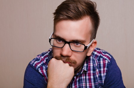 Man in dreams. Guy thinking. Portrait of man in glasses with a beard and mustache with his head propped on his handの写真素材